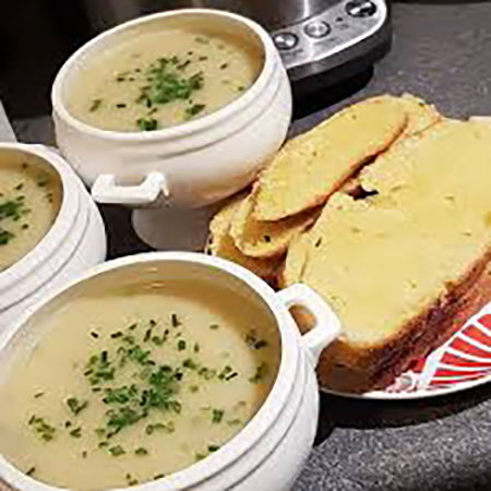 image of leek and potato soup in a bowl with bread on the side